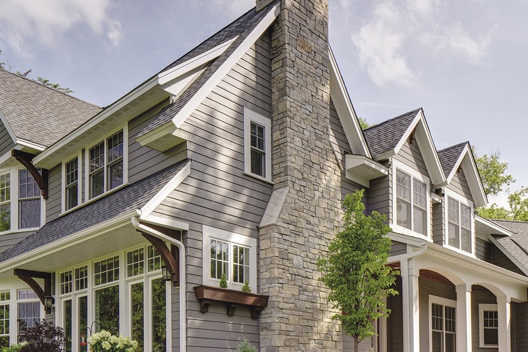 gray LP SmartSide siding on a house with white trim and stone chimney