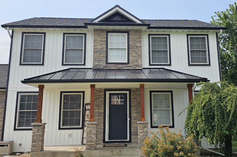 white board and batten vinyl siding with black standing seam metal roof and black window trim on a house in northern Indiana